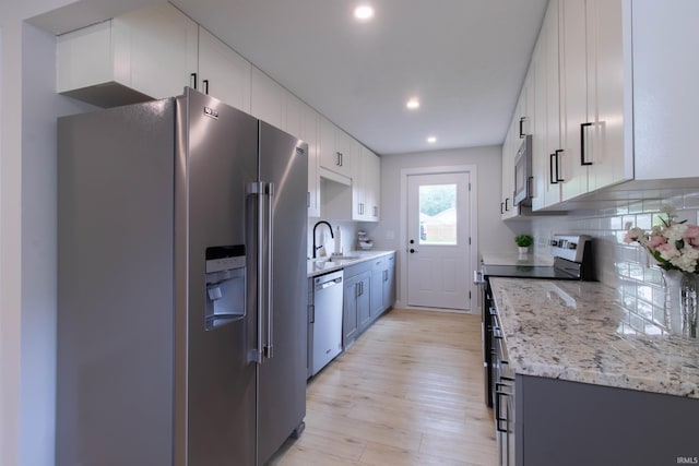 1026 S 35th St, South Bend, IN 46615 - kitchen featuring appliances with stainless steel finishes, a sink, light wood-style floors, decorative backsplash, and white cabinets
