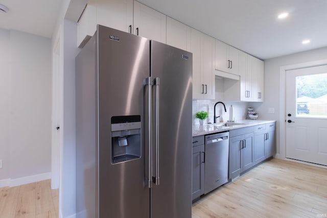 1026 S 35th St, South Bend, IN 46615 - kitchen featuring appliances with stainless steel finishes, light wood finished floors, a sink, white cabinets, and light stone countertops