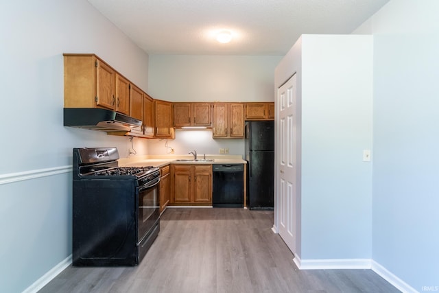 7914 Stonegate Pl, Fort Wayne, IN 46825 - kitchen featuring black appliances, under cabinet range hood, a sink, and light wood-style flooring