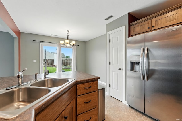 1328 Monte Carlo Dr, Huntertown, IN 46748 - kitchen featuring stainless steel fridge, a sink, brown cabinets, a chandelier, and decorative light fixtures