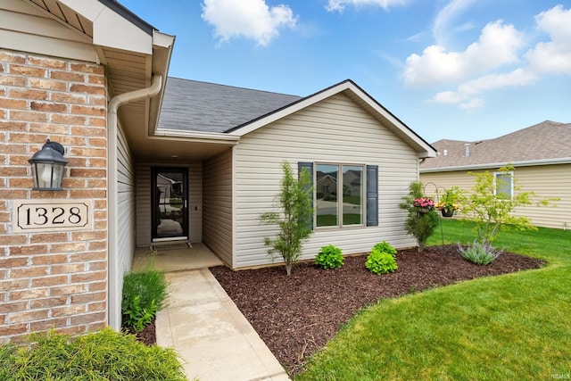 1328 Monte Carlo Dr, Huntertown, IN 46748 - view of exterior entry featuring roof with shingles and a yard
