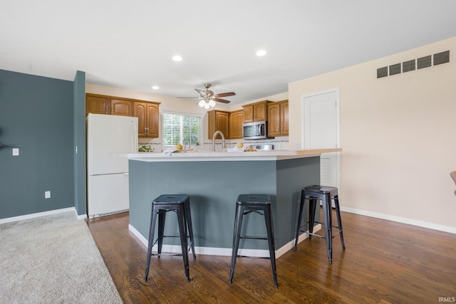 515 Cloudmont Dr, Osceola, IN 46561 - kitchen featuring freestanding refrigerator, stainless steel microwave, a kitchen island with sink, a breakfast bar area, and light countertops