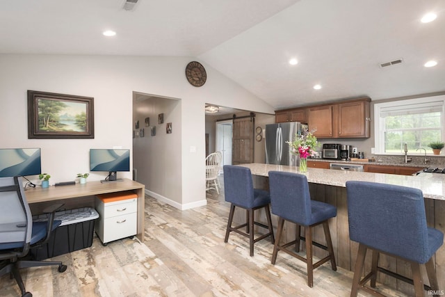 53722 Bittersweet Rd, Mishawaka, IN 46545 - kitchen featuring stainless steel appliances, light stone countertops, brown cabinets, a breakfast bar, and light wood finished floors