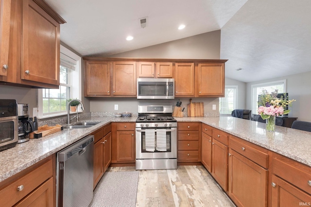53722 Bittersweet Rd, Mishawaka, IN 46545 - kitchen featuring appliances with stainless steel finishes, lofted ceiling, a sink, light wood finished floors, and brown cabinets