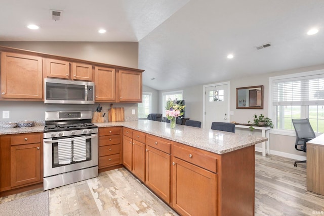53722 Bittersweet Rd, Mishawaka, IN 46545 - kitchen featuring appliances with stainless steel finishes, lofted ceiling, a peninsula, light wood finished floors, and light stone counters
