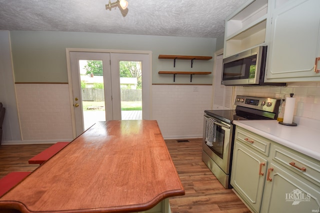 2318 W Concord Rd, Muncie, IN 47304 - kitchen featuring appliances with stainless steel finishes, butcher block counters, wood finished floors, wainscoting, and a textured ceiling
