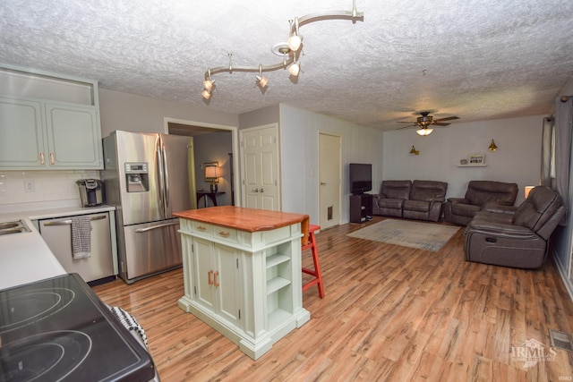 2318 W Concord Rd, Muncie, IN 47304 - kitchen with appliances with stainless steel finishes, butcher block counters, open shelves, ceiling fan, and light wood-style floors