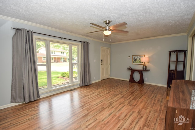 2318 W Concord Rd, Muncie, IN 47304 - unfurnished living room with wood finished floors, a ceiling fan, a textured ceiling, crown molding, and baseboards