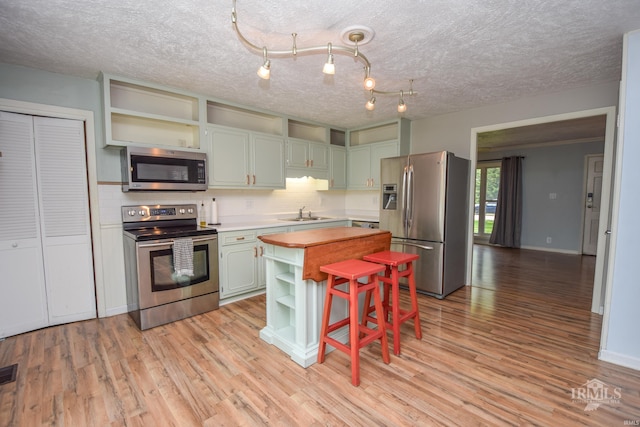 2318 W Concord Rd, Muncie, IN 47304 - kitchen featuring stainless steel appliances, open shelves, tasteful backsplash, light wood-type flooring, and a kitchen island