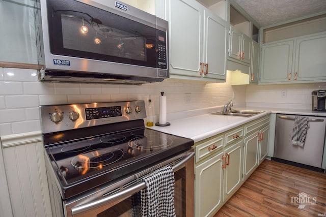 2318 W Concord Rd, Muncie, IN 47304 - kitchen with appliances with stainless steel finishes, a sink, light countertops, light wood finished floors, and decorative backsplash