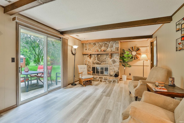 1402 Ivy Ct, North Manchester, IN 46962 - living area featuring beamed ceiling, wood finished floors, a stone fireplace, a textured ceiling, and baseboards