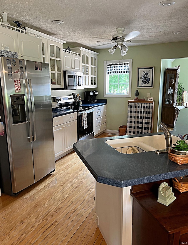 1976 Oak St, Linton, IN 47441 - kitchen featuring stainless steel appliances, a sink, light wood-type flooring, a textured ceiling, and dark countertops
