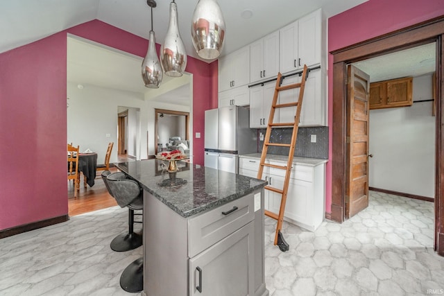 201 S 11th St, New Castle, IN 47362 - kitchen with freestanding refrigerator, white cabinetry, lofted ceiling, dark stone counters, and a center island