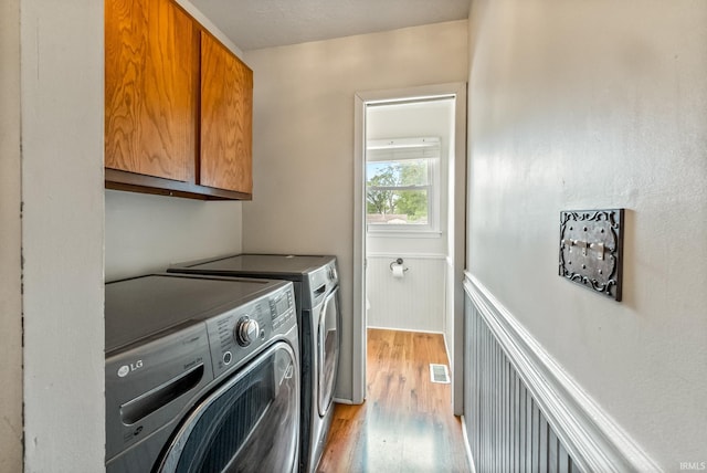 722 Biscayne Ave, Warsaw, IN 46580 - washroom with cabinet space, washing machine and dryer, light wood-style floors, and wainscoting