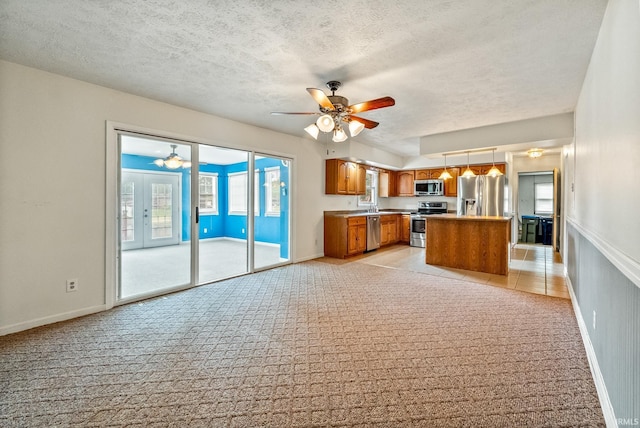 722 Biscayne Ave, Warsaw, IN 46580 - kitchen featuring appliances with stainless steel finishes, ceiling fan, brown cabinets, light carpet, and a textured ceiling