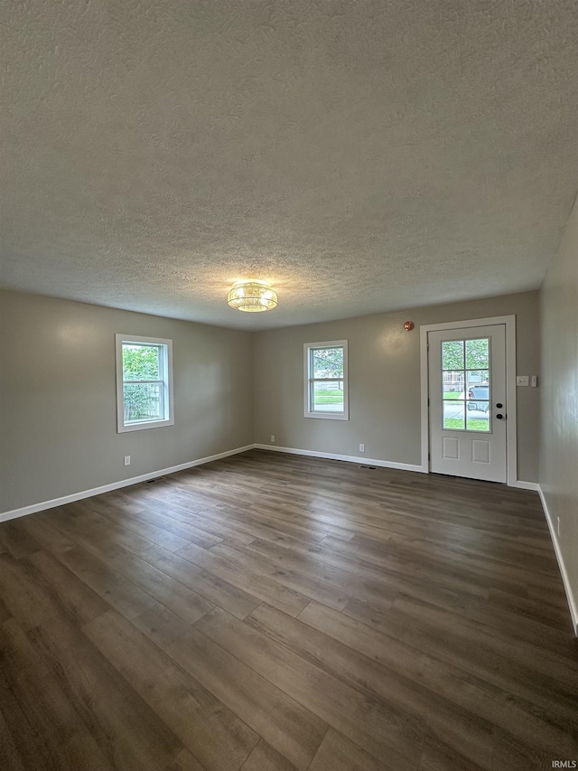 360 NE C St, Linton, IN 47441 - empty room with a textured ceiling, plenty of natural light, dark wood-type flooring, and baseboards