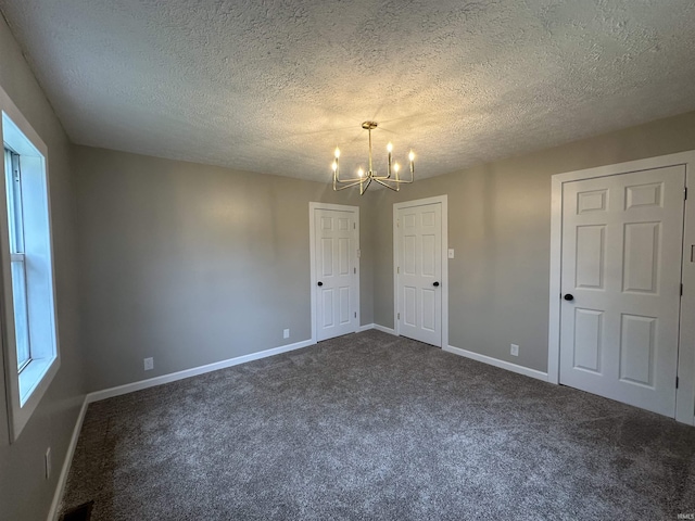 360 NE C St, Linton, IN 47441 - empty room featuring a chandelier, dark colored carpet, baseboards, and a textured ceiling