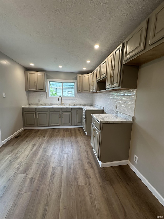 360 NE C St, Linton, IN 47441 - kitchen with dark wood-type flooring, tasteful backsplash, gray cabinetry, a sink, and a textured ceiling