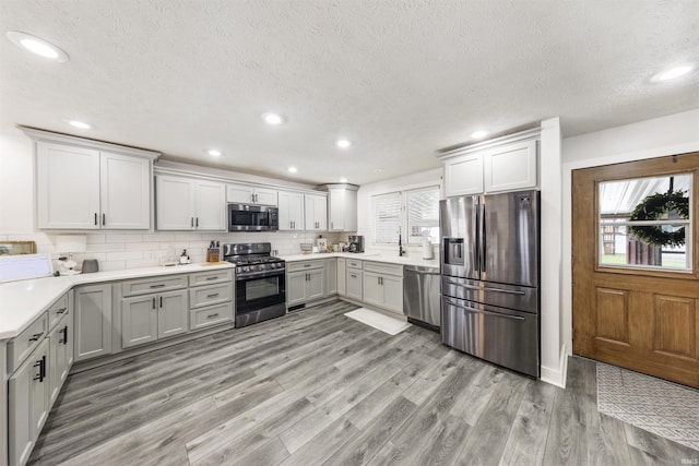 409 E Strain St, Fort Branch, IN 47648 - kitchen featuring stainless steel appliances, a textured ceiling, light wood-style floors, gray cabinetry, and tasteful backsplash