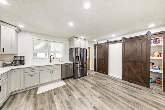 409 E Strain St, Fort Branch, IN 47648 - kitchen with appliances with stainless steel finishes, a barn door, light wood-type flooring, light countertops, and recessed lighting