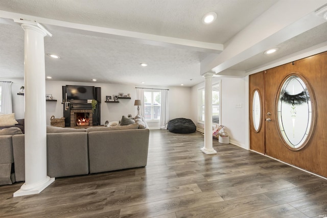 409 E Strain St, Fort Branch, IN 47648 - foyer entrance with ornate columns, a brick fireplace, beamed ceiling, a textured ceiling, and wood finished floors