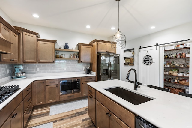 1215 Ladbrooke Dr, Evansville, IN 47725 - kitchen with stainless steel appliances, a sink, open shelves, a barn door, and light countertops