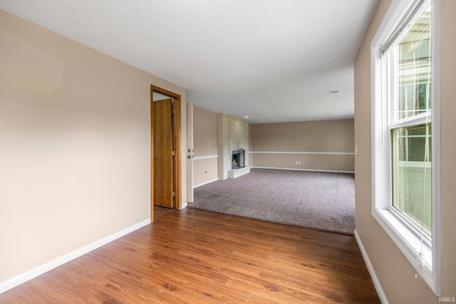 6320 Wakopa Ct, Fort Wayne, IN 46815 - unfurnished living room featuring a brick fireplace, baseboards, and wood finished floors
