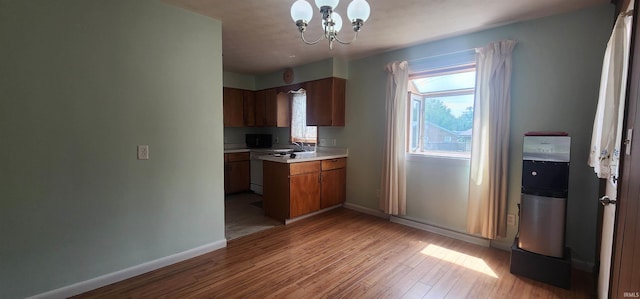 2703 Bosworth Dr, Fort Wayne, IN 46805 - kitchen featuring light countertops, a chandelier, a sink, light wood-type flooring, and baseboards