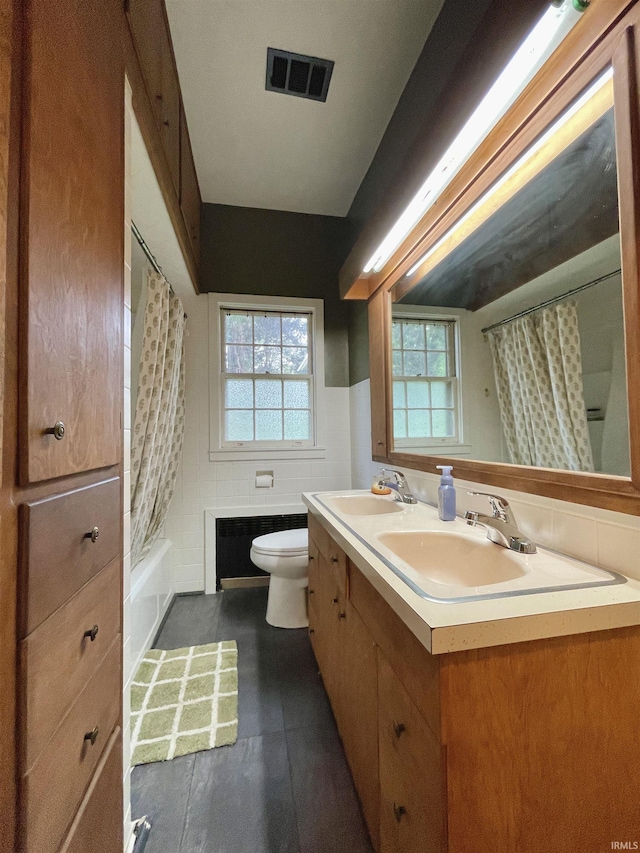 5425 Lincoln Ave, Evansville, IN 47715 - bathroom featuring toilet, double vanity, healthy amount of natural light, tile walls, and shower / bathtub combination with curtain