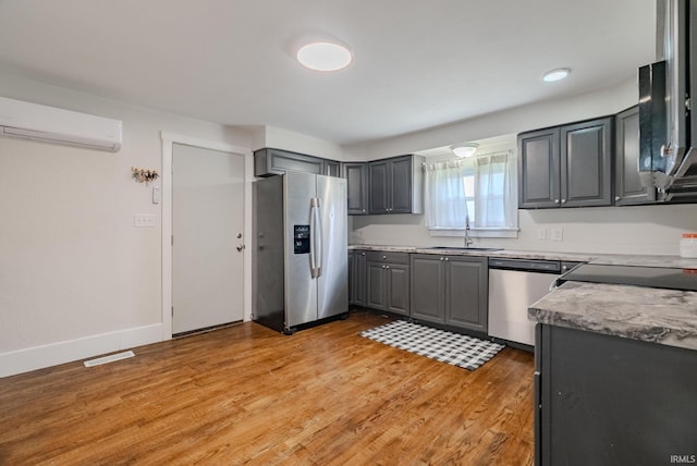 8694 W 1000 S Unit 35, Lafontaine, IN 46940 - kitchen with stainless steel appliances, a sink, a wall mounted air conditioner, gray cabinetry, and light wood-type flooring
