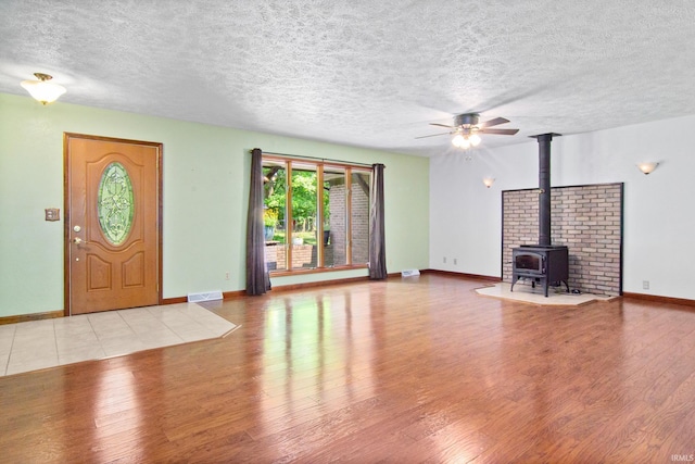 2299 Brown Chapel Rd, Boonville, IN 47601 - unfurnished living room featuring wood finished floors, a wood stove, a textured ceiling, a ceiling fan, and baseboards