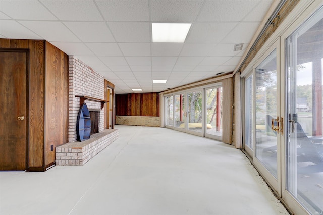 50 Reindeer Cir, Santa Claus, IN 47579 - unfurnished living room with wooden walls, concrete flooring, a fireplace, and a drop ceiling