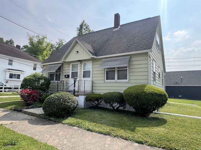 83 9th St, Logansport, IN 46947 - view of front of house with a chimney, a front lawn, and a shingled roof