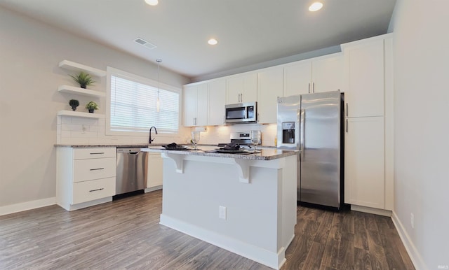 916 Cameo Dr, Evansville, IN 47711 - kitchen with appliances with stainless steel finishes, a kitchen bar, backsplash, dark wood finished floors, and recessed lighting