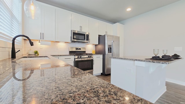 916 Cameo Dr, Evansville, IN 47711 - kitchen with stainless steel appliances, a sink, dark stone countertops, wood finished floors, and white cabinetry