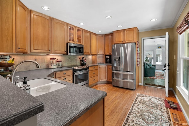 3709 Capilano Dr, West Lafayette, IN 47906 - kitchen featuring appliances with stainless steel finishes, a sink, crown molding, decorative backsplash, and light wood-type flooring