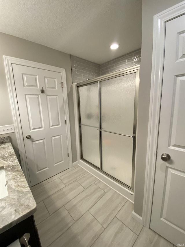 4310 E Duffy Dr, Syracuse, IN 46567 - full bathroom with vanity, a shower stall, a textured ceiling, baseboards, and recessed lighting