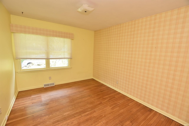1200 S Longwood Dr, Bloomington, IN 47401 - spare room featuring wood-type flooring, wallpapered walls, and baseboards