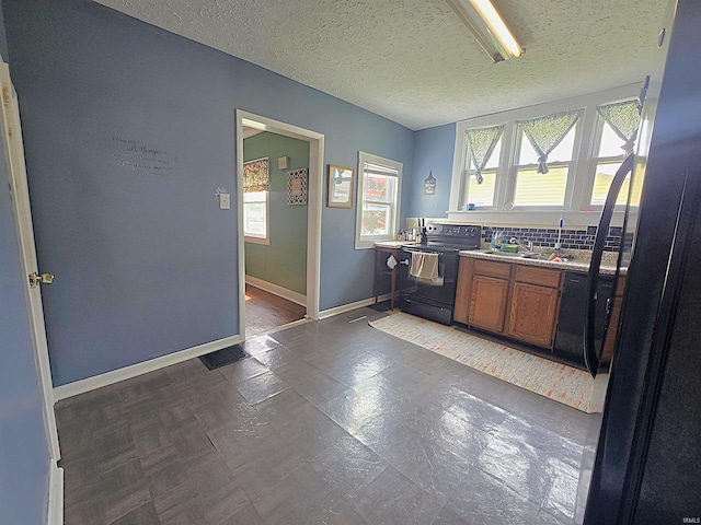 220 W Main St, Greentown, IN 46936 - kitchen featuring black range with electric stovetop, brown cabinets, baseboards, a textured ceiling, and freestanding refrigerator