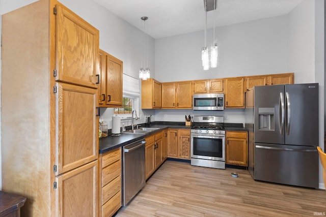 5405 N Andrea Dr, Bloomington, IN 47404 - kitchen featuring appliances with stainless steel finishes, a sink, dark countertops, light wood finished floors, and a high ceiling