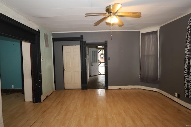 744 First St, Huntington, IN 46750 - empty room featuring light wood finished floors, a ceiling fan, a barn door, baseboards, and crown molding