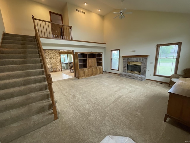 404 Ridge Ct, Ossian, IN 46777 - unfurnished living room featuring a glass covered fireplace, carpet flooring, stairs, a ceiling fan, and healthy amount of natural light