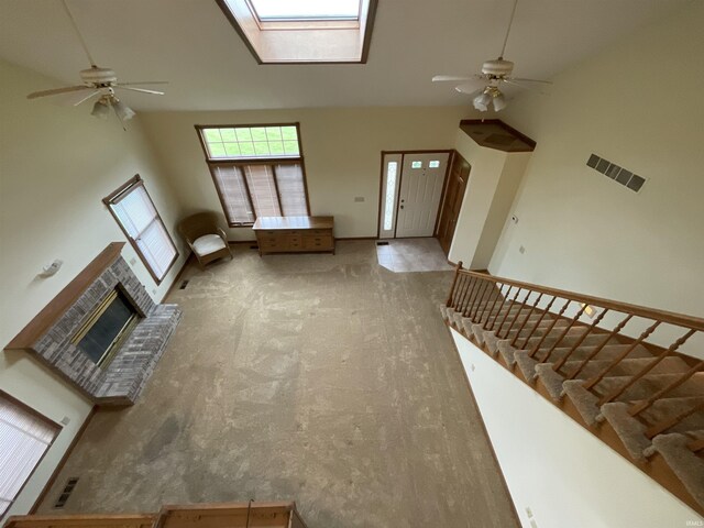 404 Ridge Ct, Ossian, IN 46777 - unfurnished living room featuring a ceiling fan, a skylight, a brick fireplace, stairs, and high vaulted ceiling