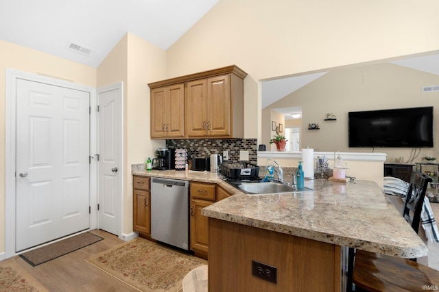 2082 Hemlock Ln, Warsaw, IN 46580 - kitchen with stainless steel dishwasher, lofted ceiling, a sink, a peninsula, and light wood-style flooring