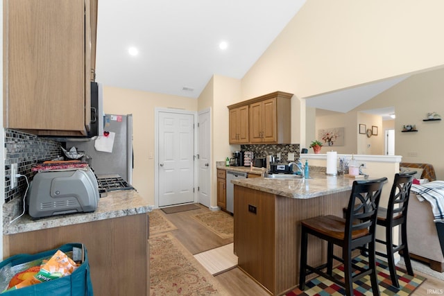 2082 Hemlock Ln, Warsaw, IN 46580 - kitchen with a sink, stainless steel appliances, a kitchen breakfast bar, decorative backsplash, and a peninsula
