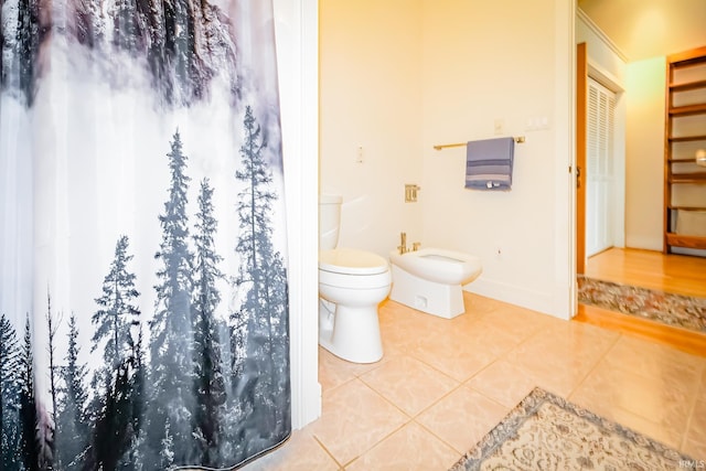 2910 W Devon Rd, Muncie, IN 47304 - bathroom featuring toilet, a bidet, tile patterned floors, baseboards, and a shower with curtain