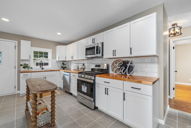 9129 Winchester Rd, Fort Wayne, IN 46819 - kitchen with butcher block counters, stainless steel appliances, light tile patterned flooring, a sink, and recessed lighting