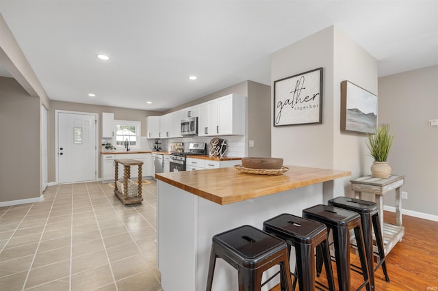 9129 Winchester Rd, Fort Wayne, IN 46819 - kitchen featuring stainless steel appliances, wooden counters, a breakfast bar area, baseboards, and backsplash