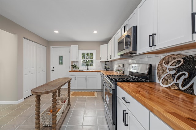 9129 Winchester Rd, Fort Wayne, IN 46819 - kitchen featuring wood counters, appliances with stainless steel finishes, backsplash, light tile patterned floors, and white cabinets