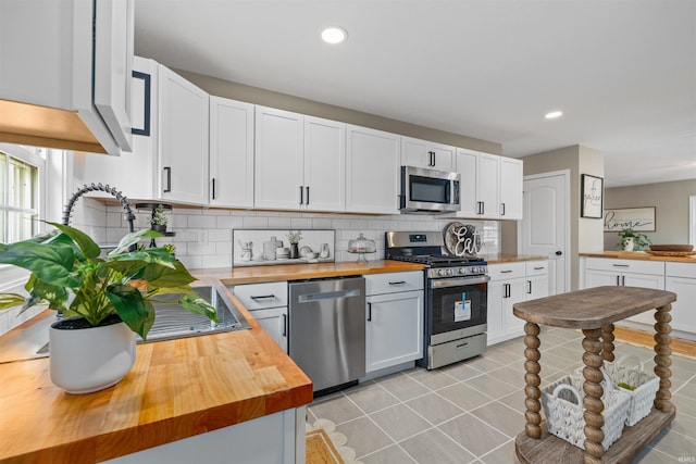 9129 Winchester Rd, Fort Wayne, IN 46819 - kitchen featuring wooden counters, stainless steel appliances, backsplash, light tile patterned floors, and recessed lighting